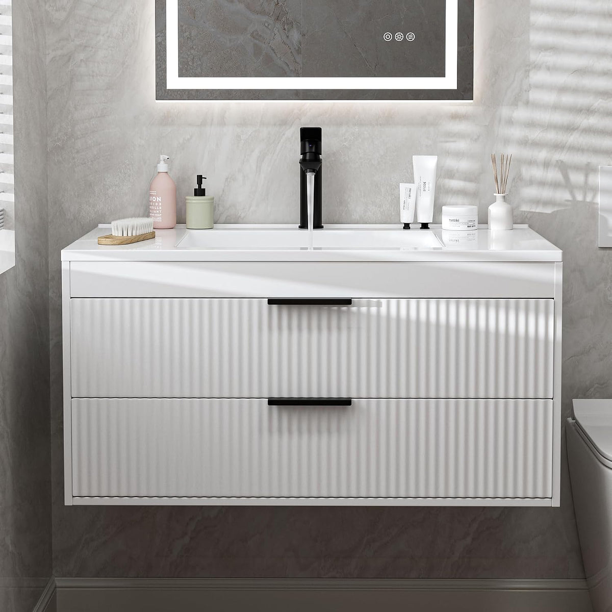 Wall-mounted white vanity with two ribbed drawers, black handles and faucet, integrated white sink and toiletries on top.