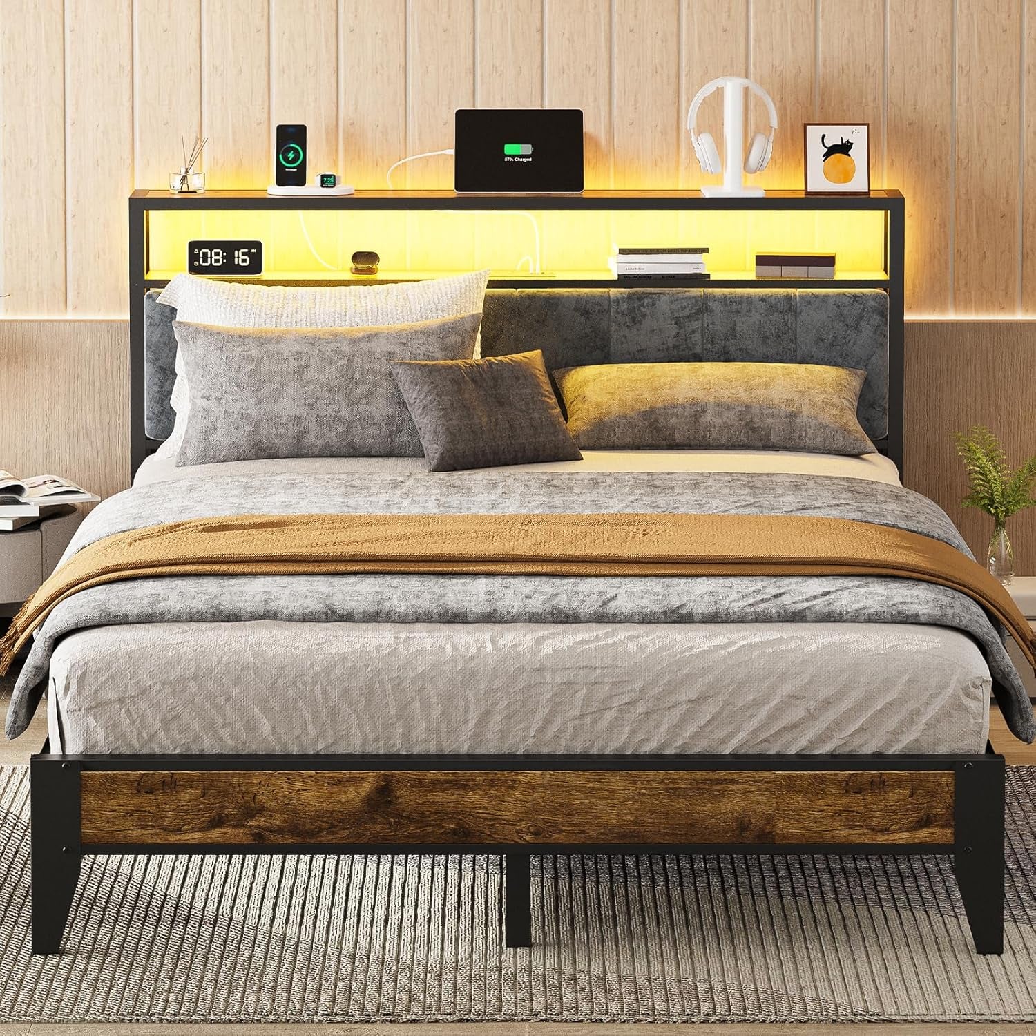 Close front view of bed showing upholstered headboard panels, illuminated shelf with accessories and a wood-framed footboard.