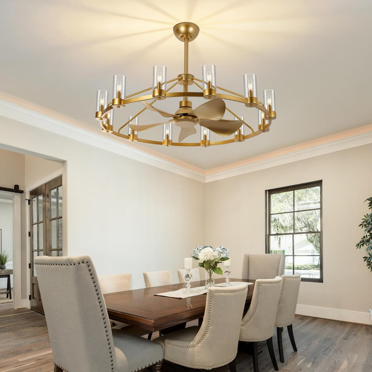 Dining room view with a gold wagon-wheel chandelier fan mounted over a wooden table and upholstered chairs.