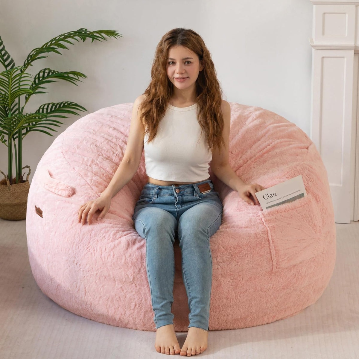 Person seated on a large pink faux-fur bean bag chair showing the rounded back and low profile