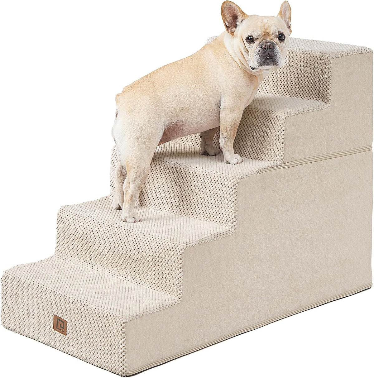 Beige four-step foam stairs seen at an angle with a small fawn French bulldog standing on the middle steps.