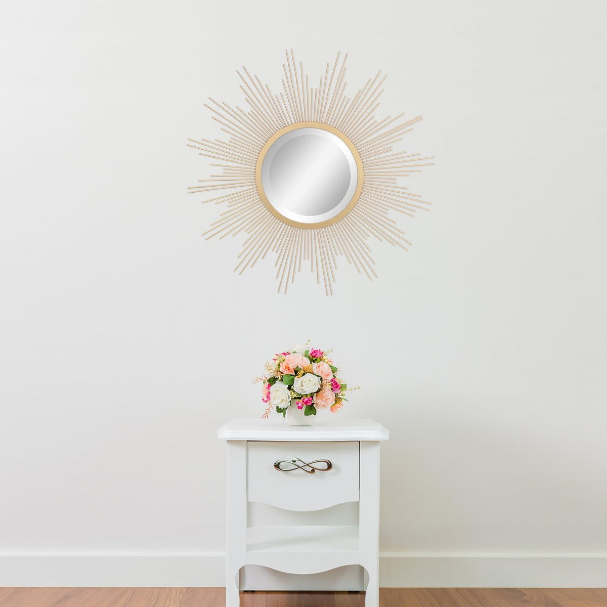 Antique gold starburst mirror hung above a white nightstand in a neutral styled interior