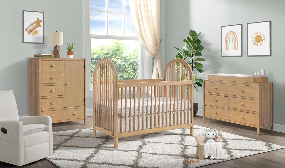 Nursery scene showing the honey wood crib centered with matching dresser and changing table