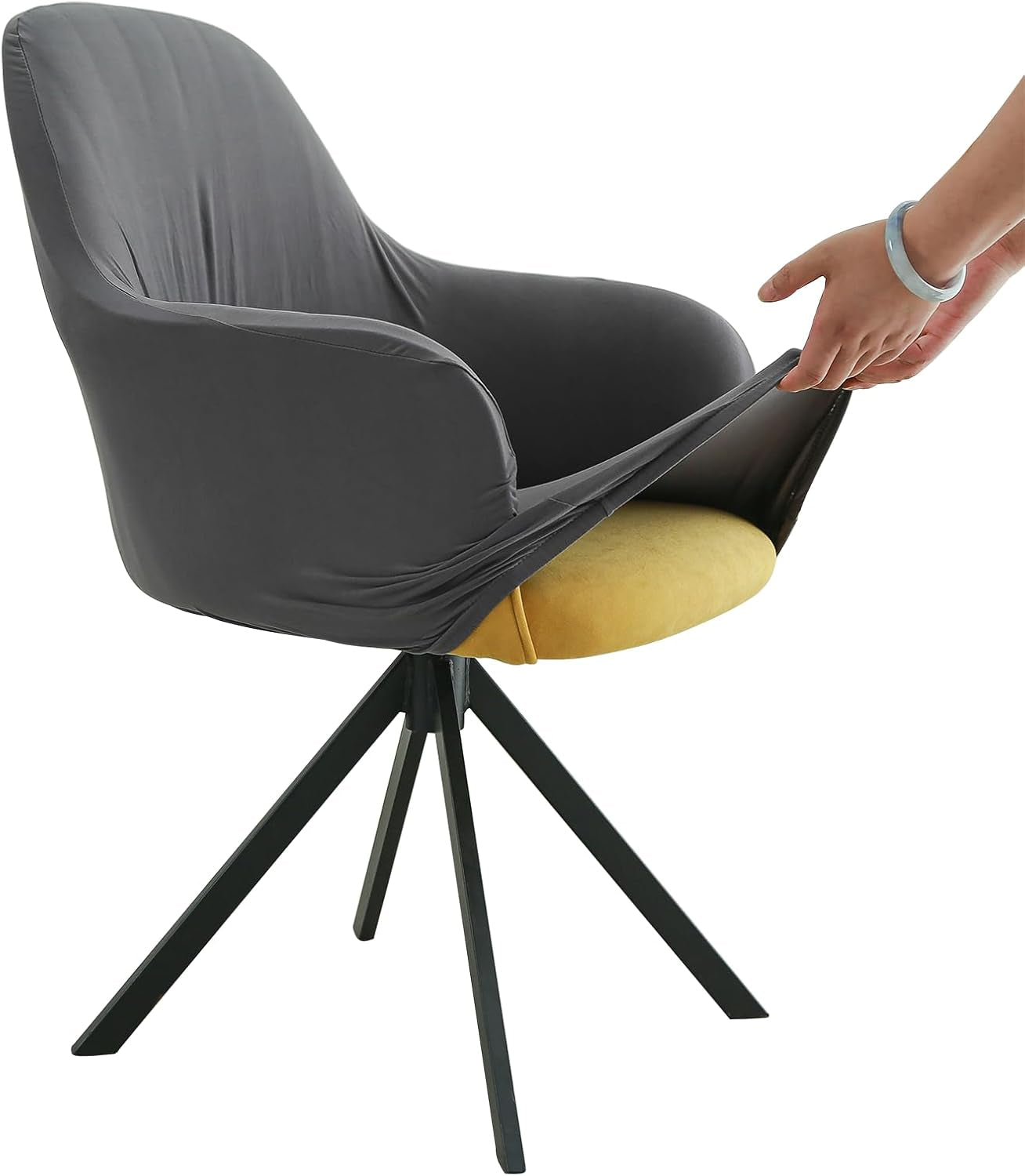Side view of a charcoal gray stretch cover being pulled over an armchair seat by a pair of hands.