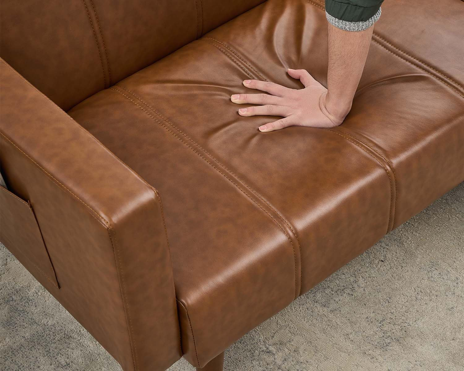 Close-up of brown PU leather seat surface with hand pressing the cushion