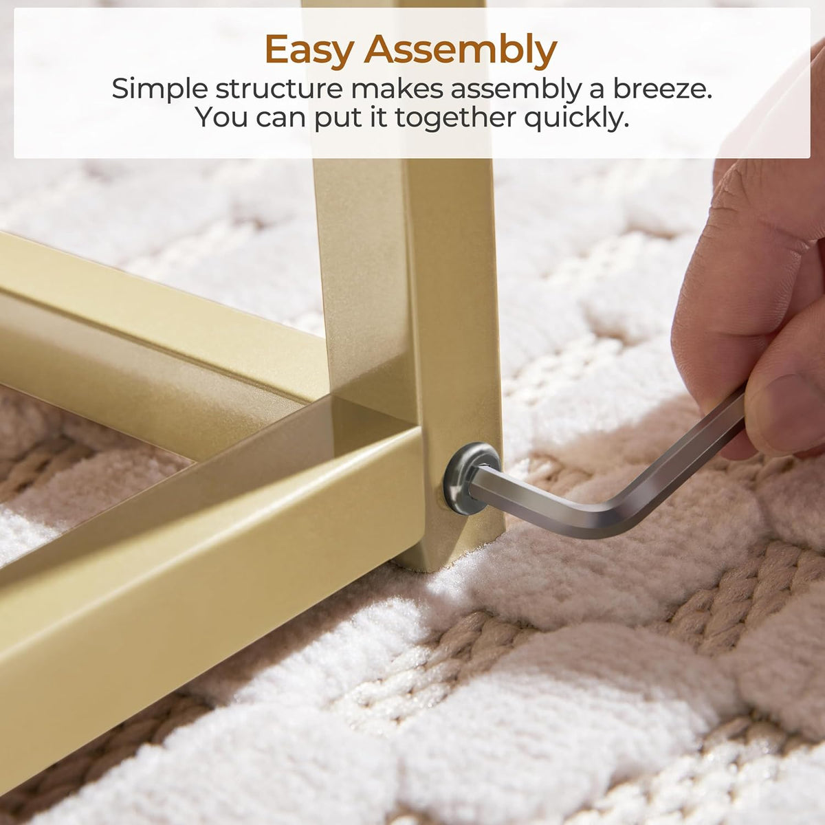 Tight shot of a hand using an Allen wrench to secure a bolt at the base of the gold table leg