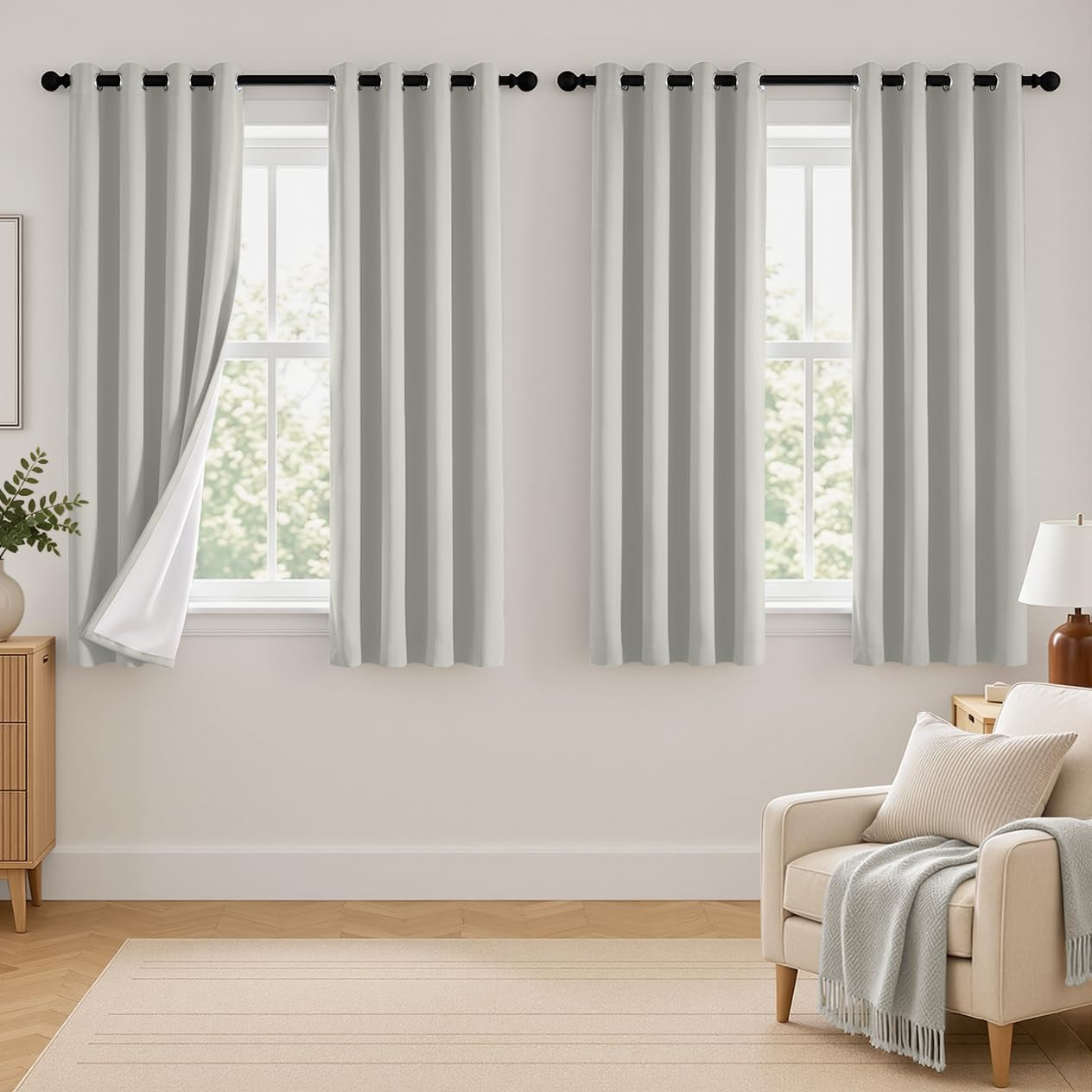 Two light gray grommet curtain panels over two narrow windows, left panel slightly turned to show white backing