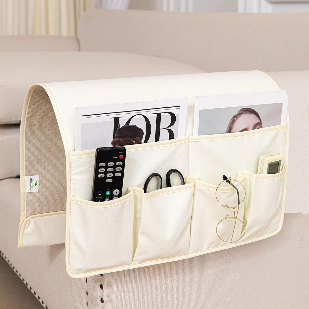 Cream-colored caddy close-up focused on the top pockets with a remote and scissors visible.