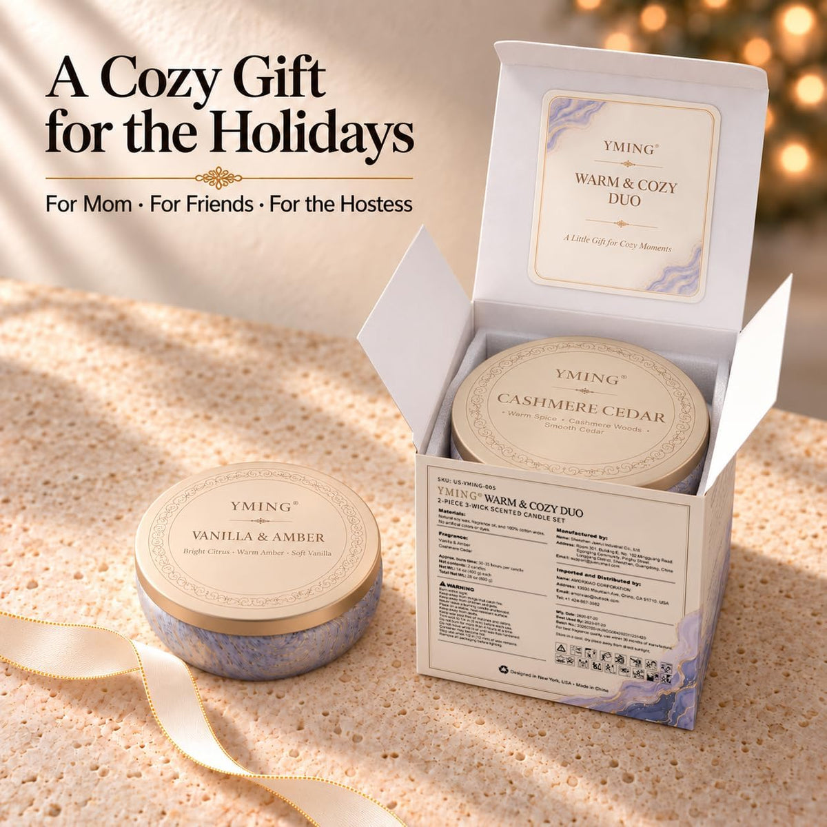 Open gift box revealing a marbled-tin candle inside and a second tin beside it on a speckled tabletop with ribbon