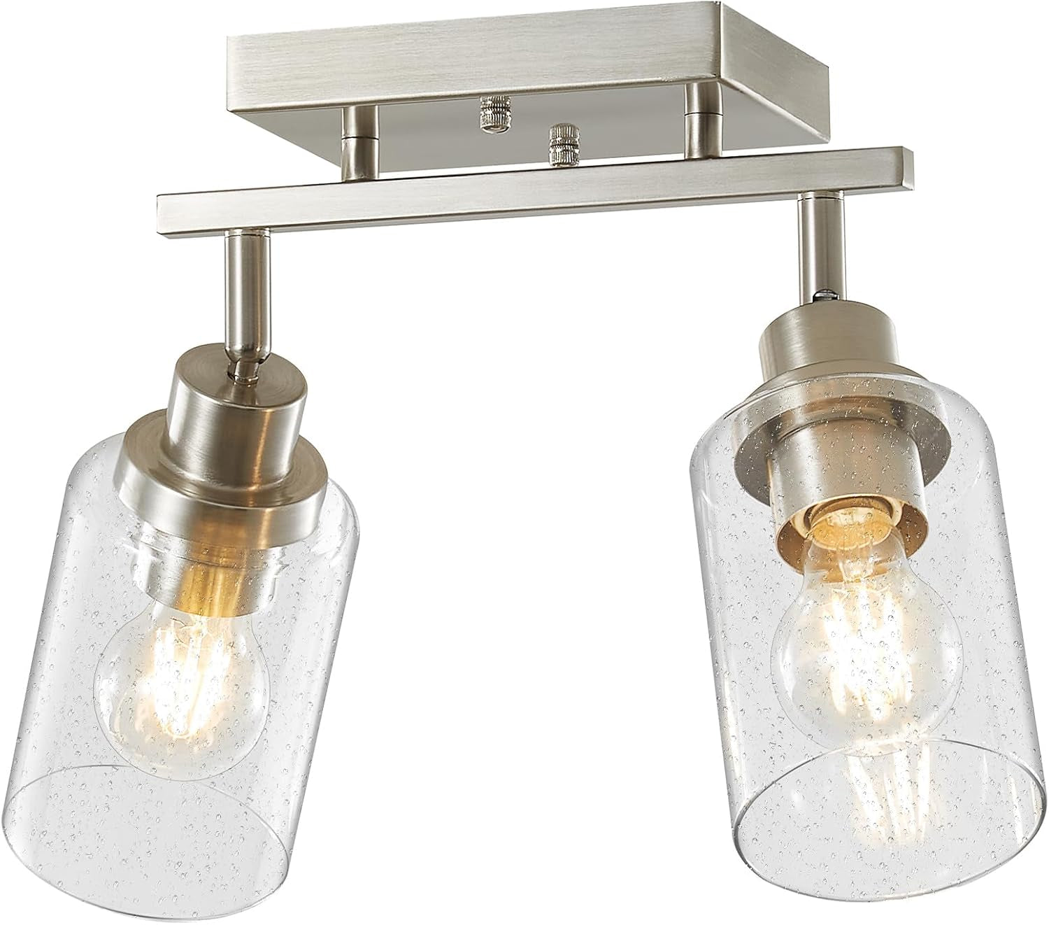 Tight low-angle close-up of two brushed nickel lamp posts with seeded glass shades and glowing bulbs