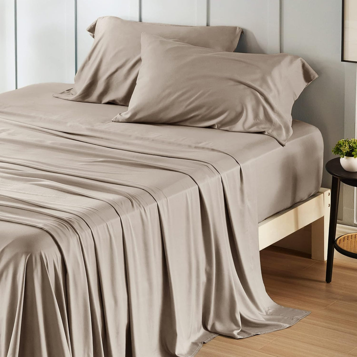 Bed with light taupe sheets and two pillowcases, sheets flowing to the floor