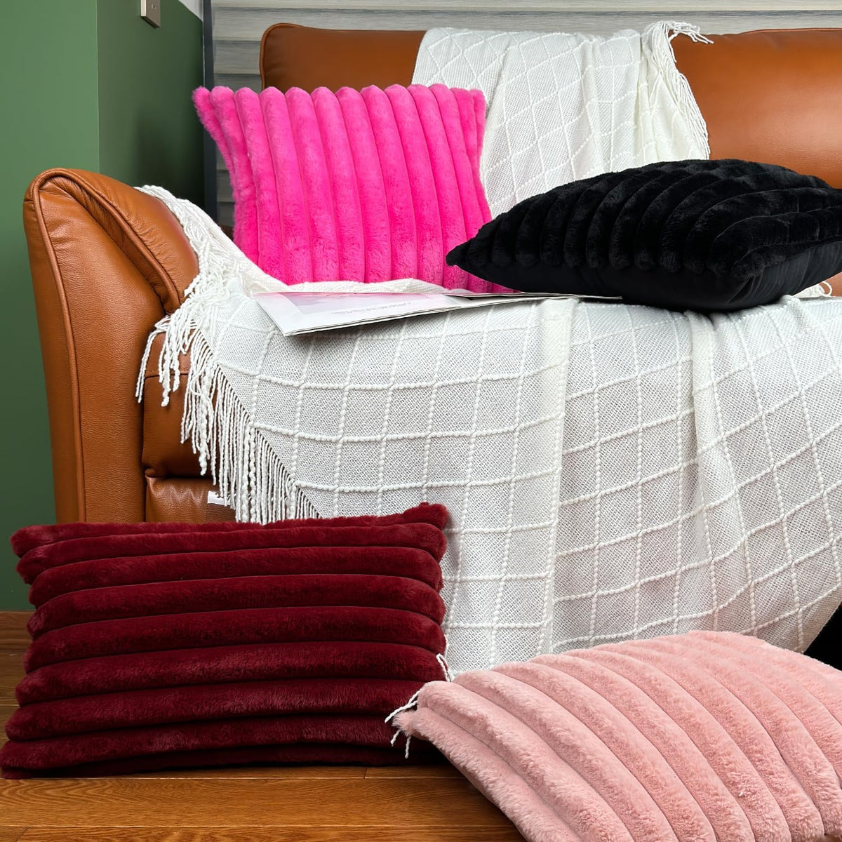 Bright pink and black ribbed faux-fur covers arranged on a draped sofa cushion, with folded burgundy covers at the edge.