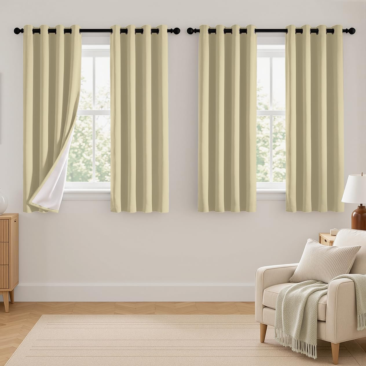 Two sets of beige curtains on two windows in a living area with armchair and lamp at right