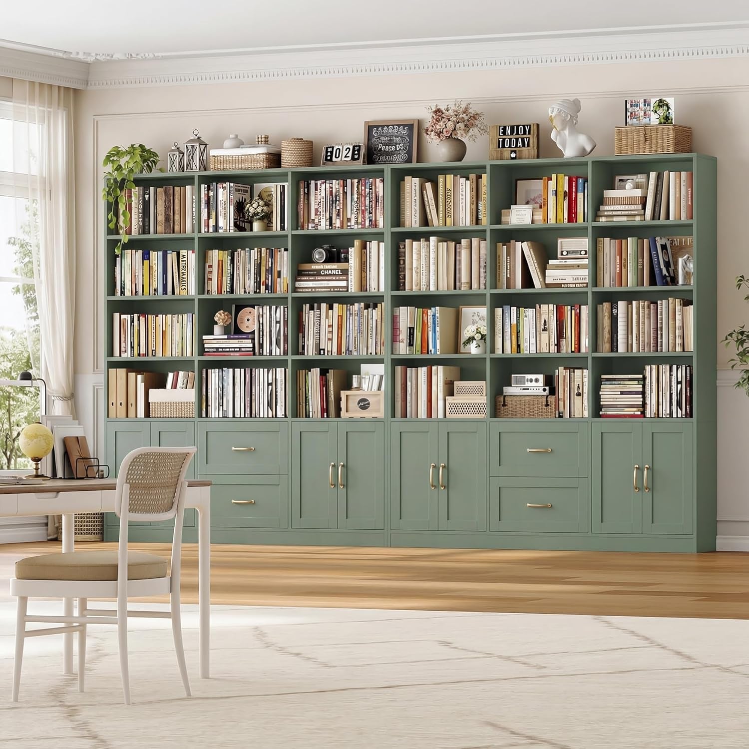 Green triple-wide bookshelf in a bright living room setting with chair and wood floor.