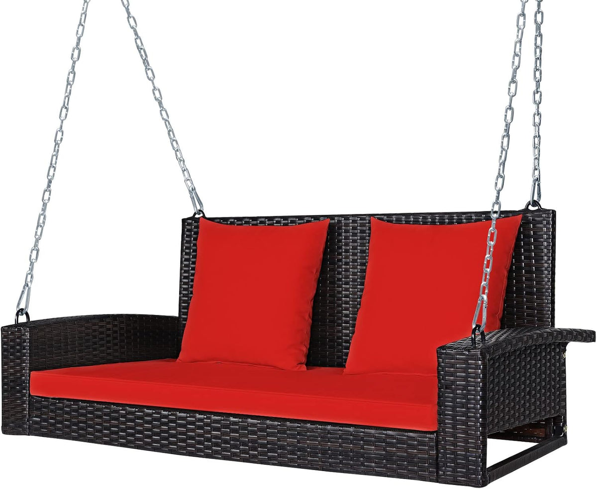 Three-quarter front view of the dark wicker hanging swing with bright red seat cushion and two red back pillows.