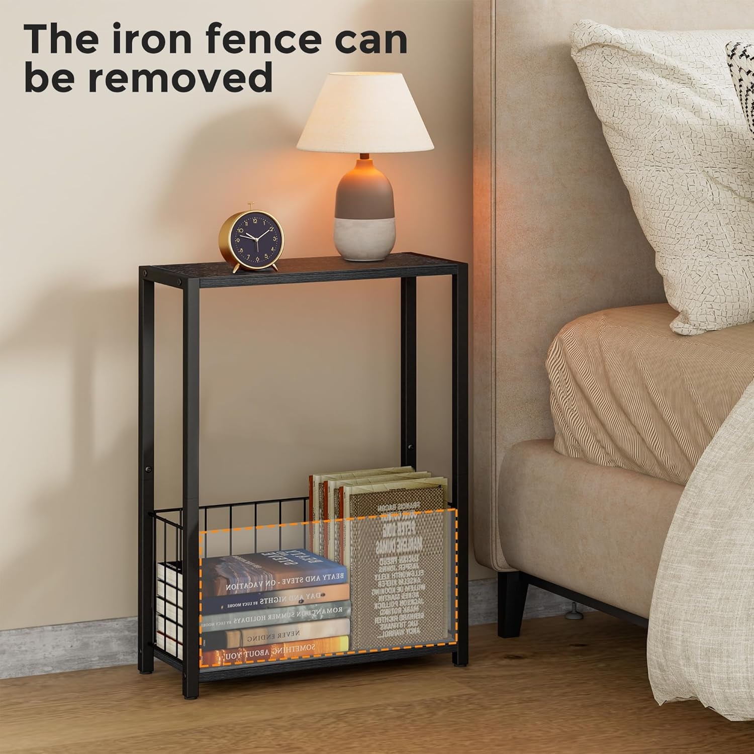Black narrow side table next to a bed holding a lamp and clock, with removable wire basket filled with books.
