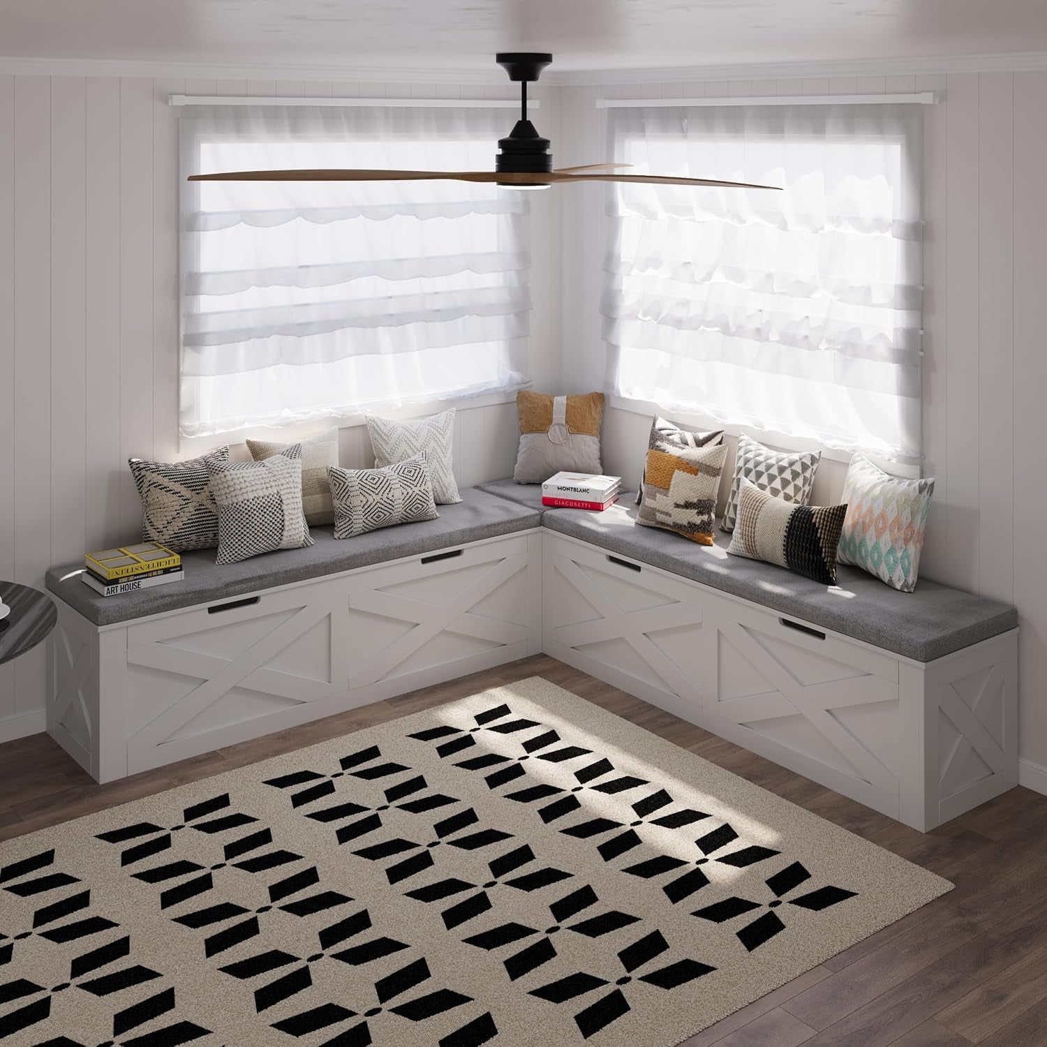 White L-shaped storage bench with grey seat cushion and mixed patterned pillows in a bright corner nook