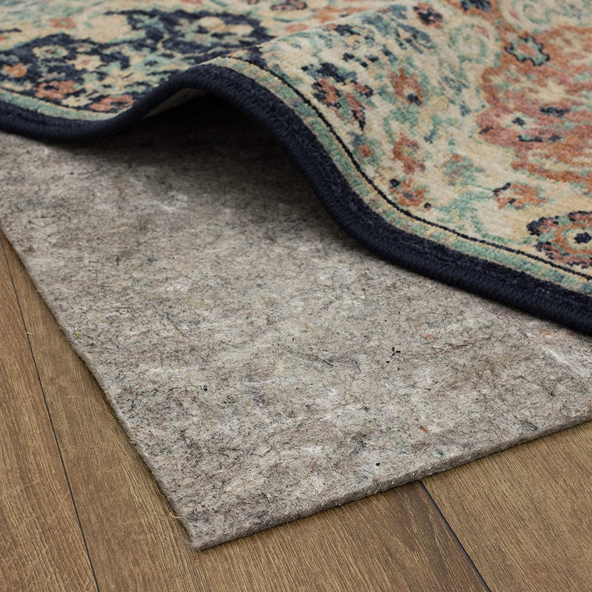 Low-angle close-up of the rug edge resting on a mottled gray felt pad, highlighting the pad's compressed texture.