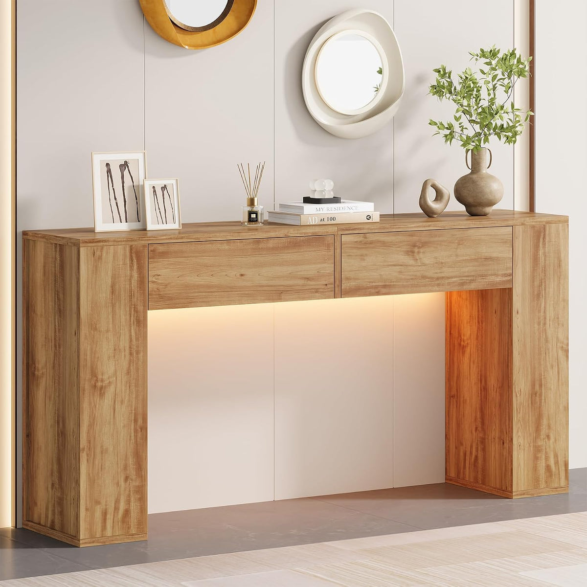 Light wood-finish console table styled with a plant, small sculptures and two wall mirrors above.