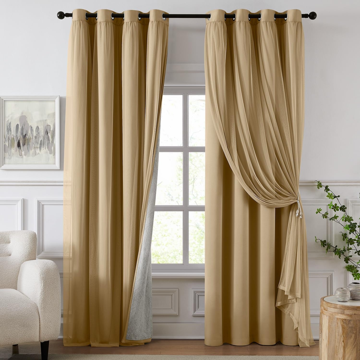 Window framed by warm gold blackout panels with a sheer overlay tied back beside a wooden side table.