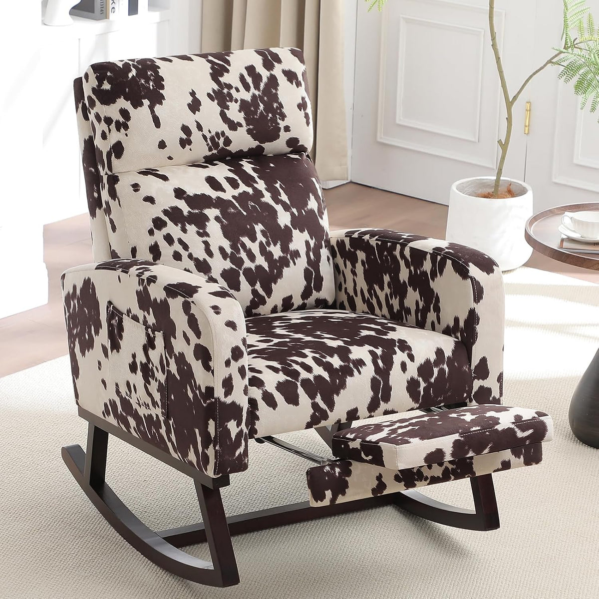 Black-and-white cowhide patterned rocking chair with dark wood rockers and pulled-out footrest