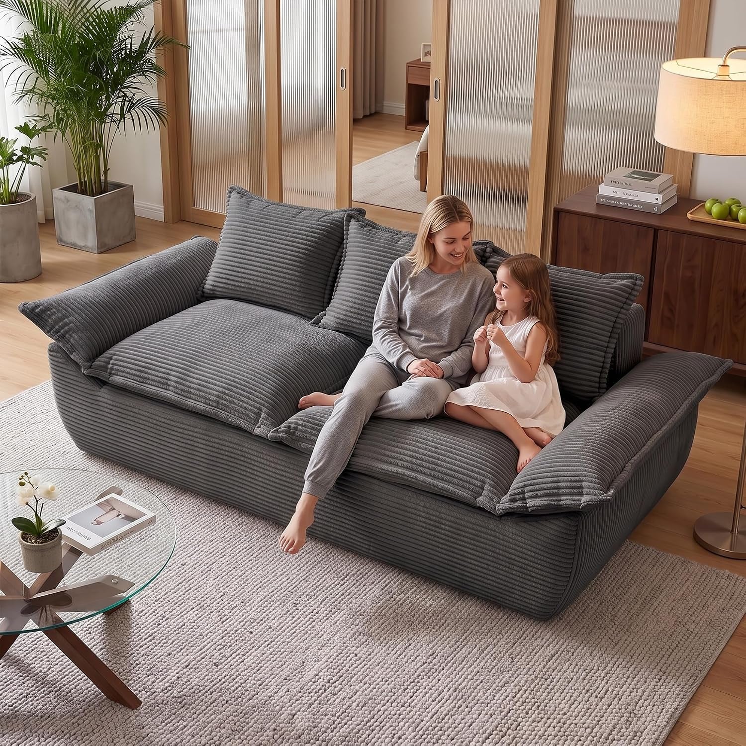 Same living room showing a charcoal corduroy two-seater sofa with a woman and child seated