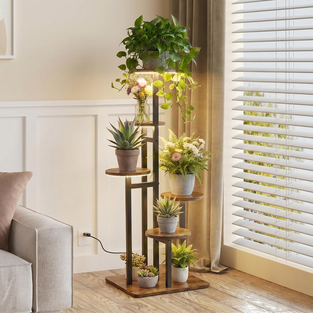 Side view highlighting the stand's round shelves, visible power cord plugged into a wall outlet and slatted window blinds