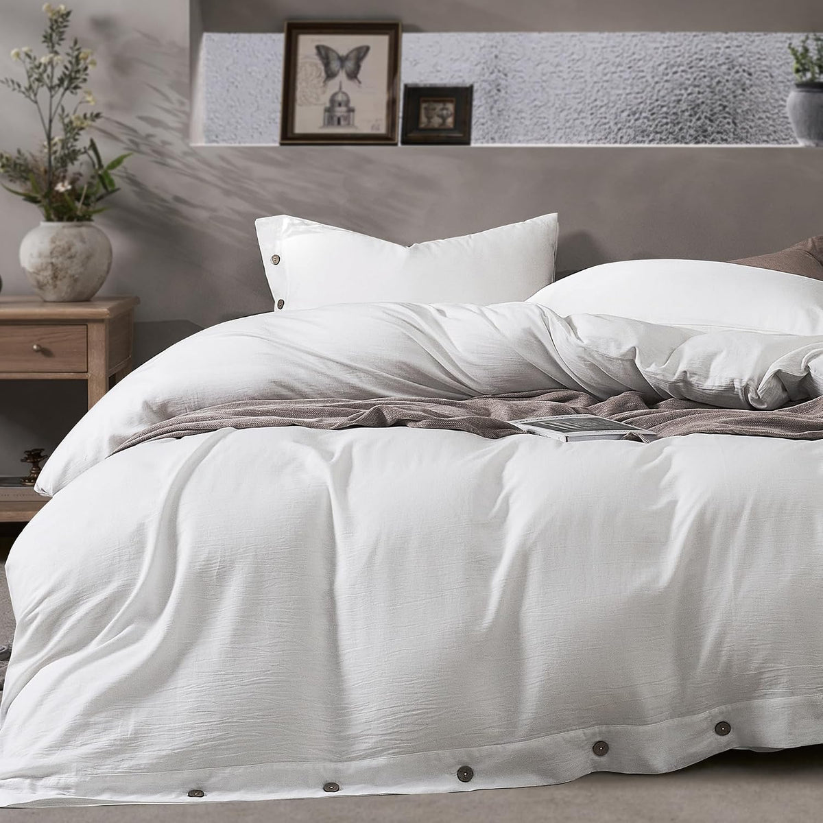 Styled close view of a white duvet and pillow with a textured brown throw draped across the bed.