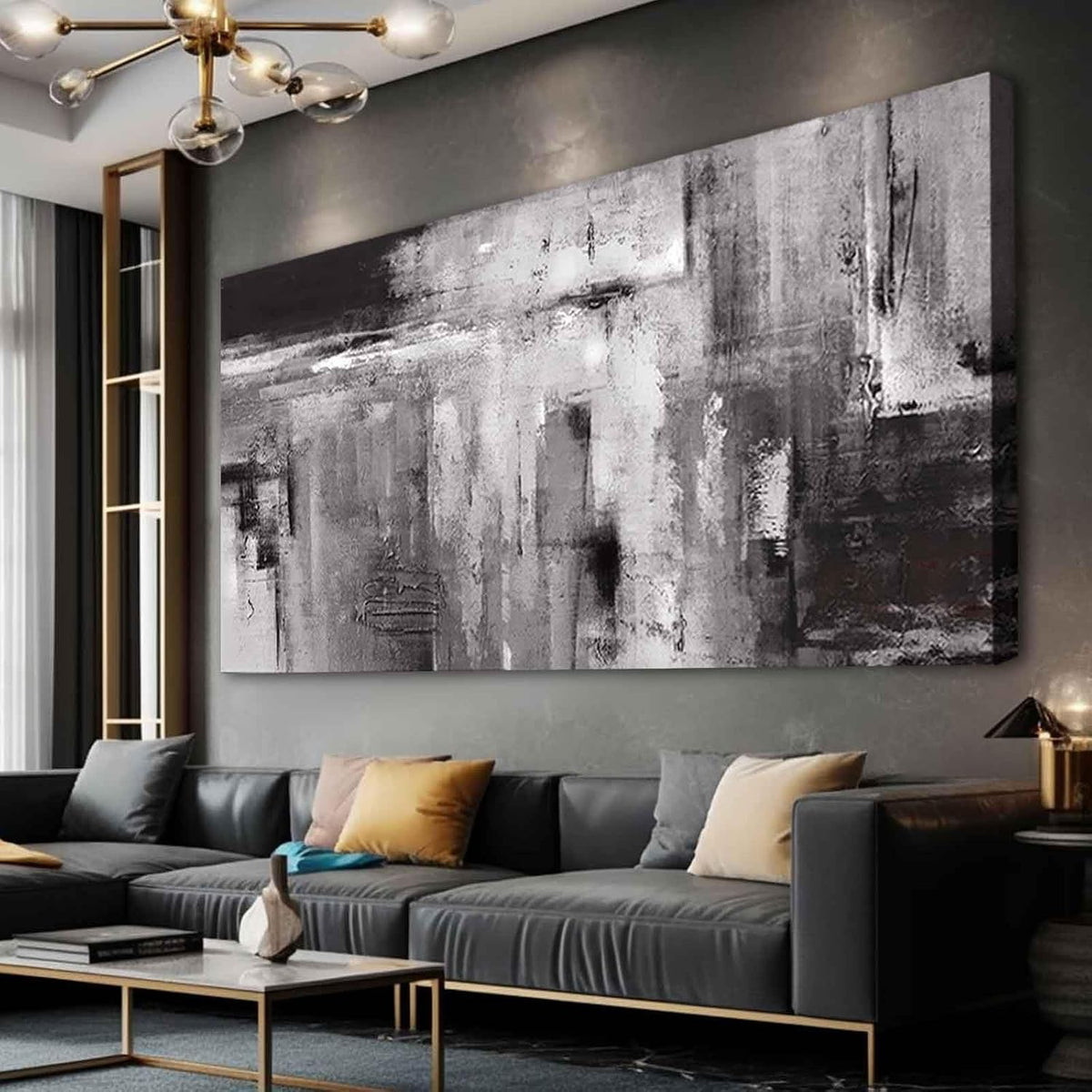 Angled living-room view of a large monochrome textured canvas above a dark gray sectional with mustard and gray pillows.