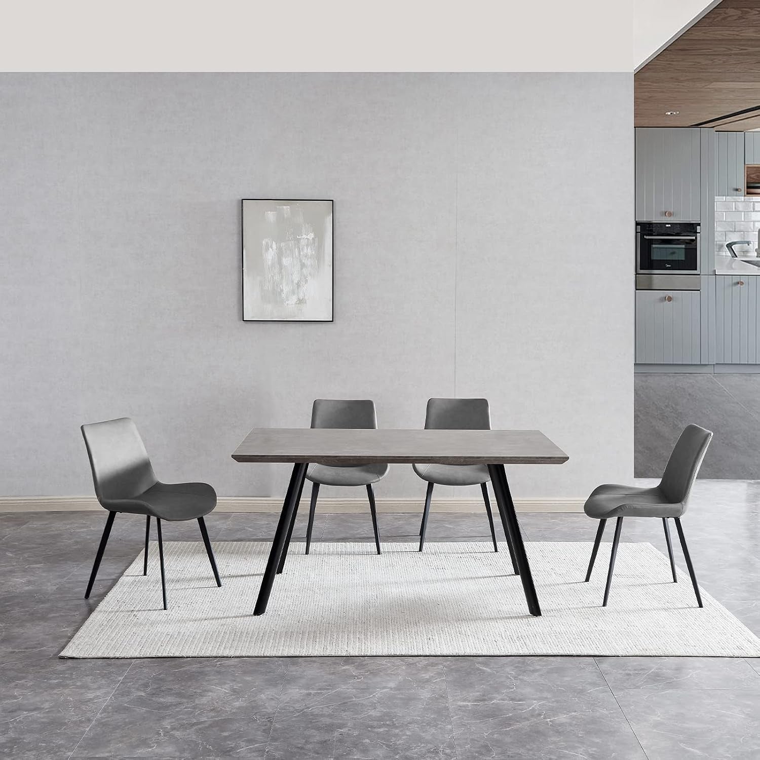 Gray dining table with four dark gray PU chairs on a light rug in a minimalist room with framed art.