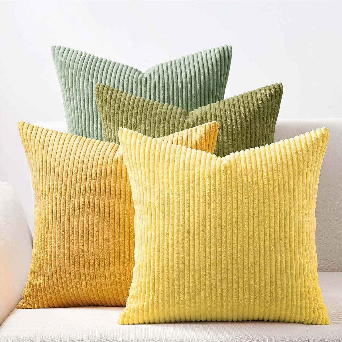 Four ribbed square pillows in yellow and green shades displayed on a light couch