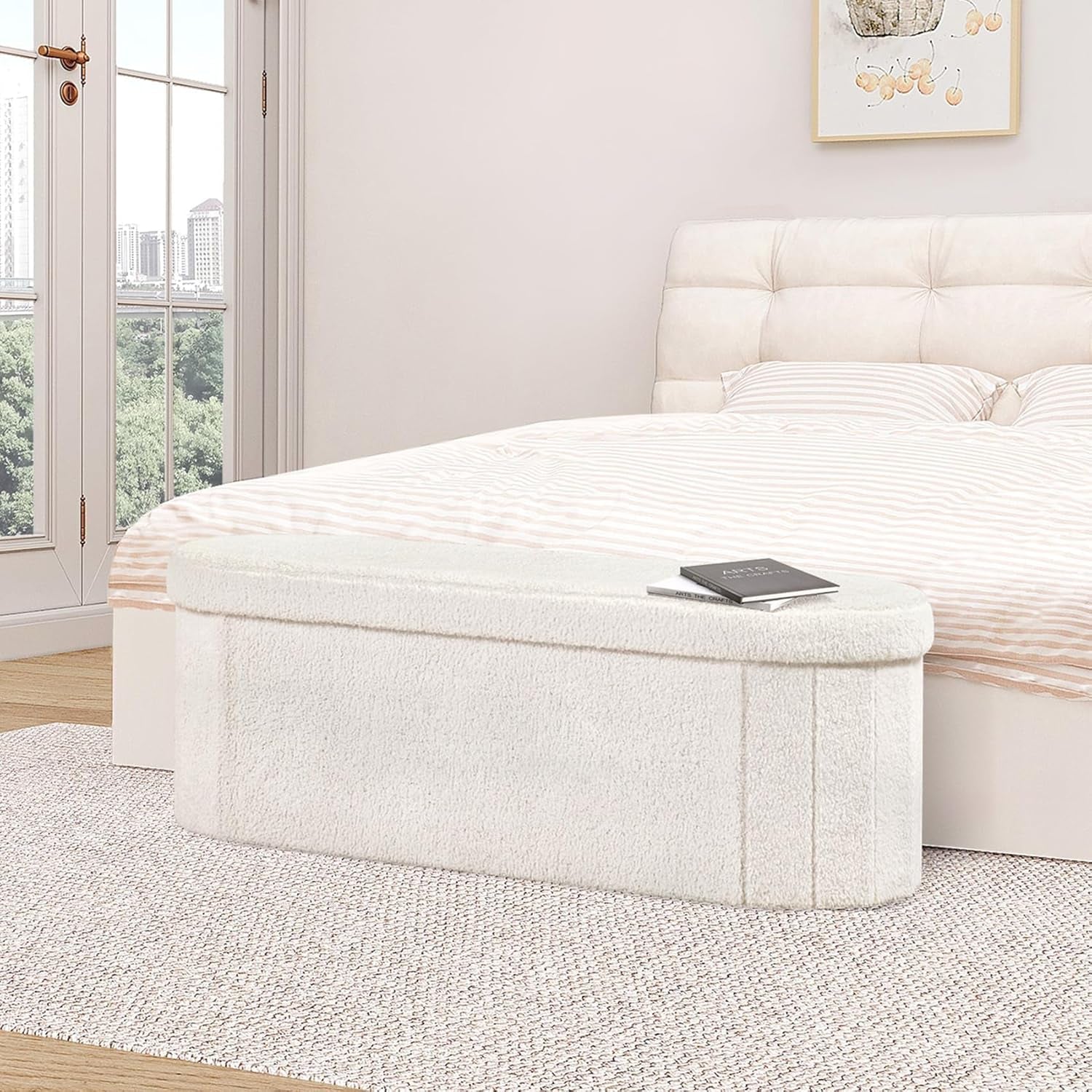 Cream sherpa storage bench positioned at the foot of a bed with a book on top