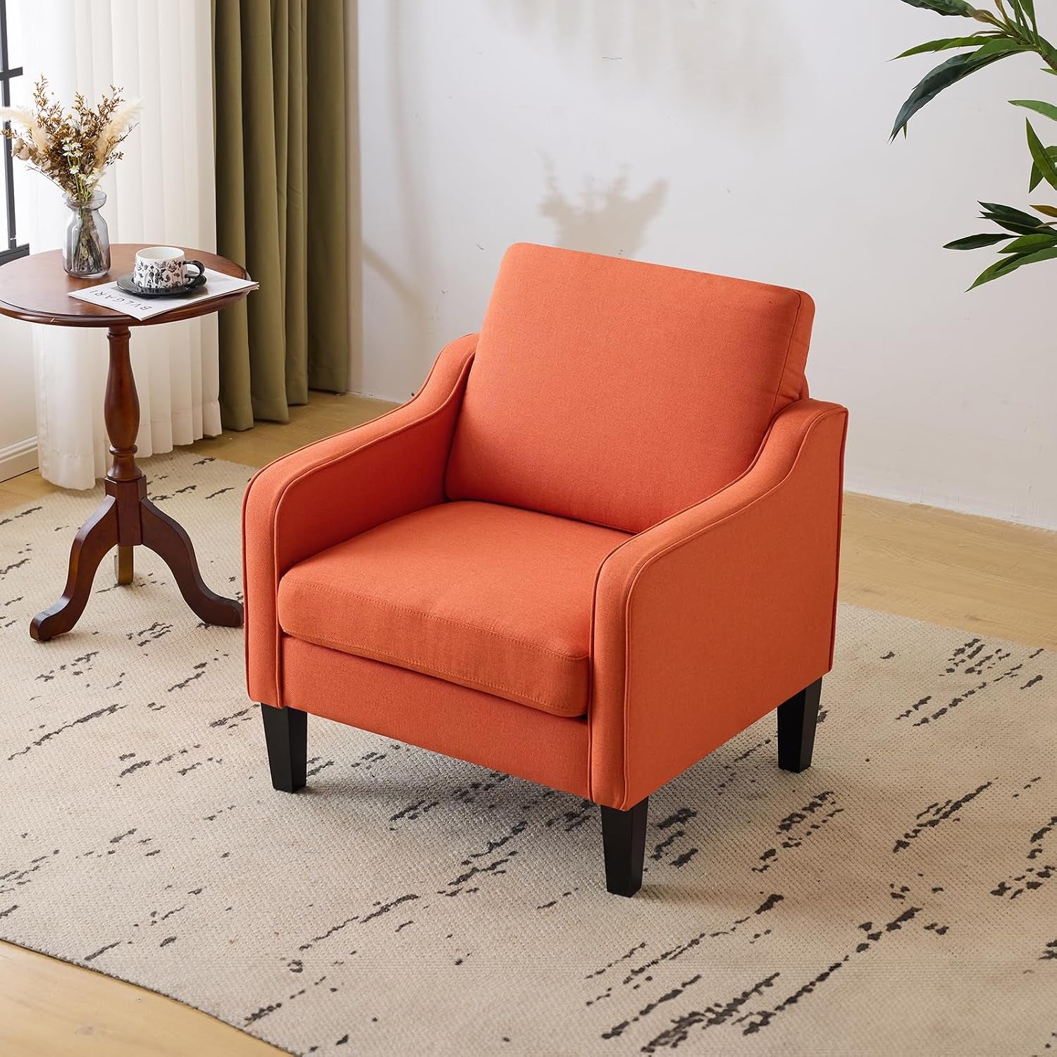 Orange upholstered accent chair with solid dark wood legs in a bright room setting