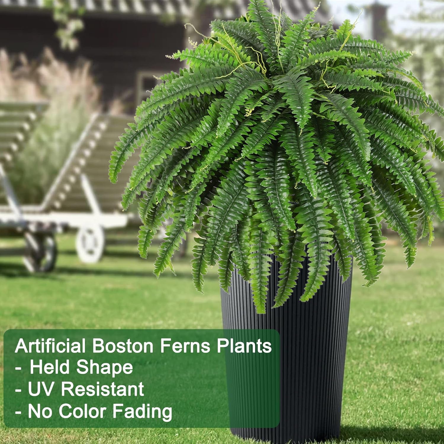 Green artificial Boston fern bush in a tall dark ribbed planter on a grassy area