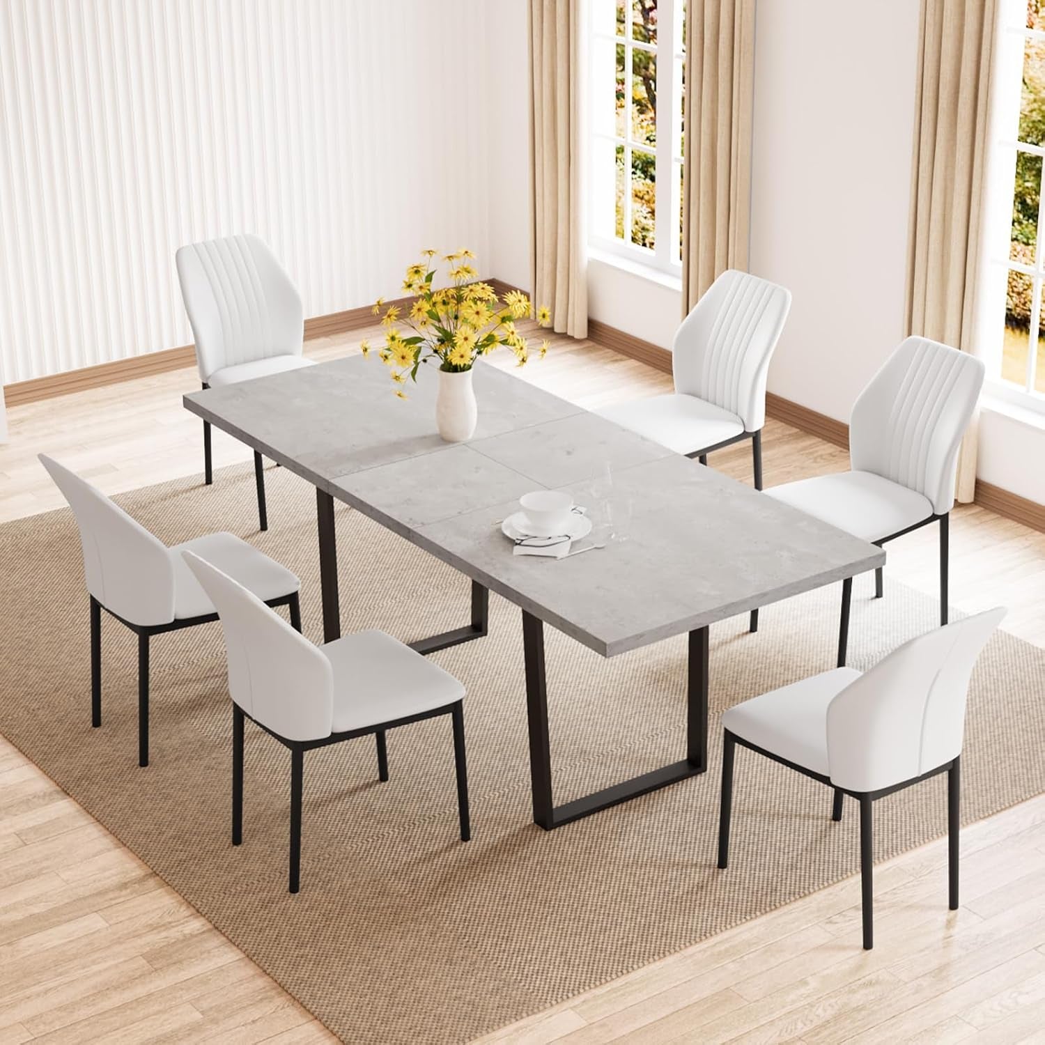 Angled overhead view of a concrete-look tabletop with six white PU chairs on a woven rug.