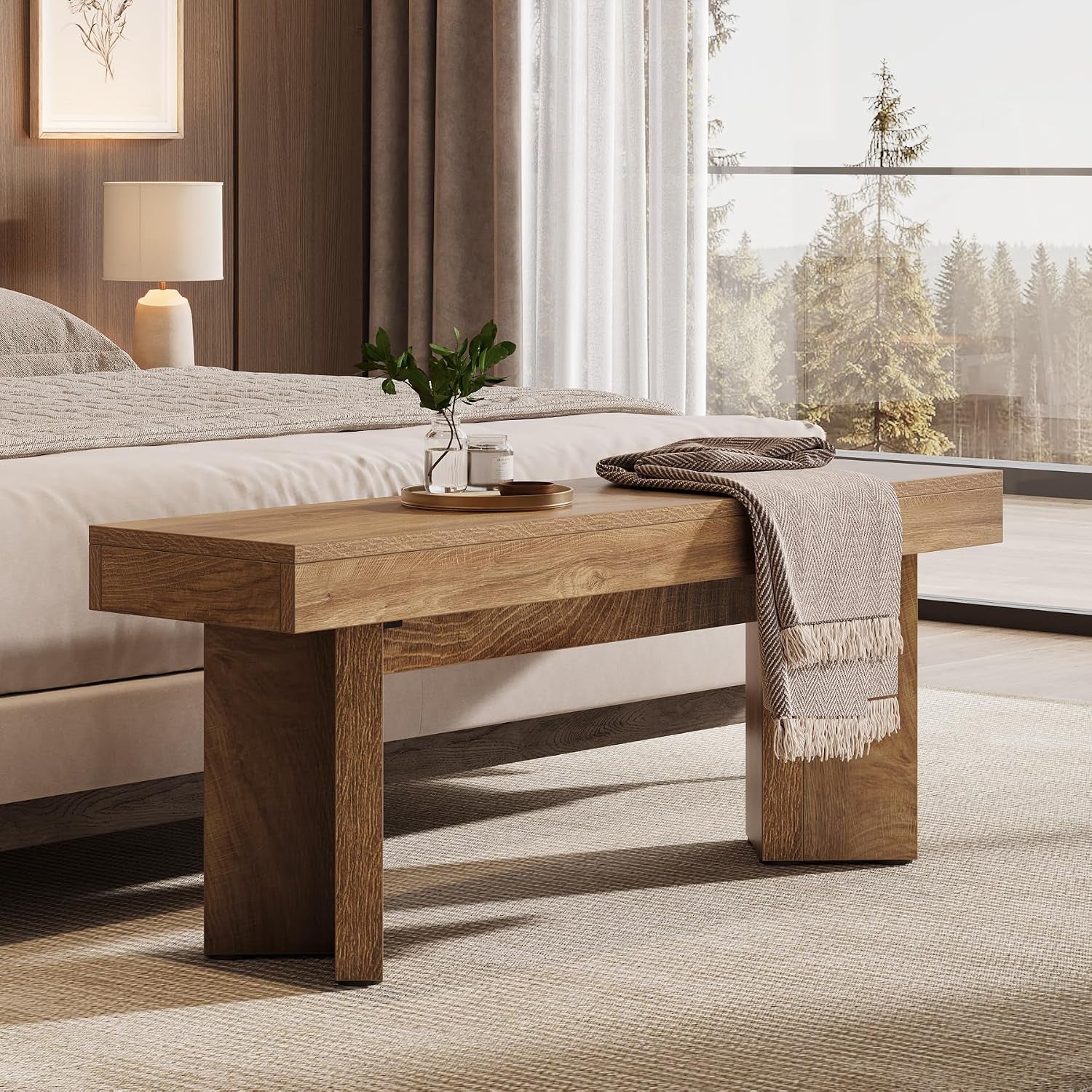 Rustic brown bench placed at the end of a bed with a throw and decorative tray in a bedroom