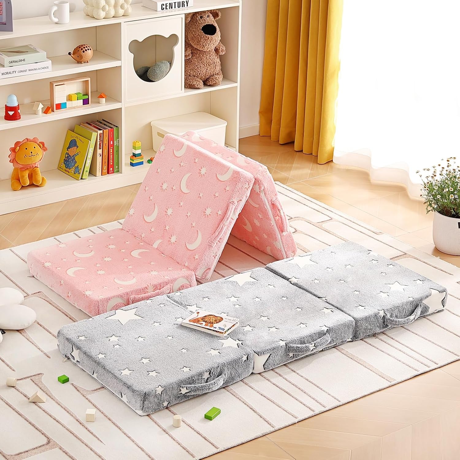 Kids tri-fold mattresses on a rug in a sunlit playroom, pink moon set folded into a tent and gray star set laid flat.