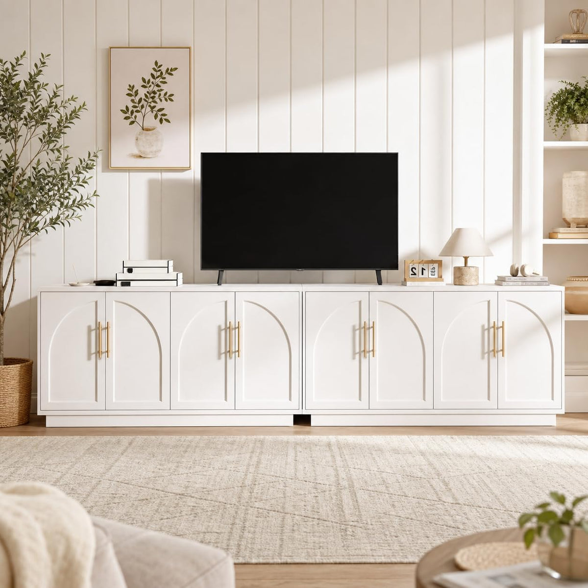 Low white sideboard with arched doors and TV on top in a bright, paneled room