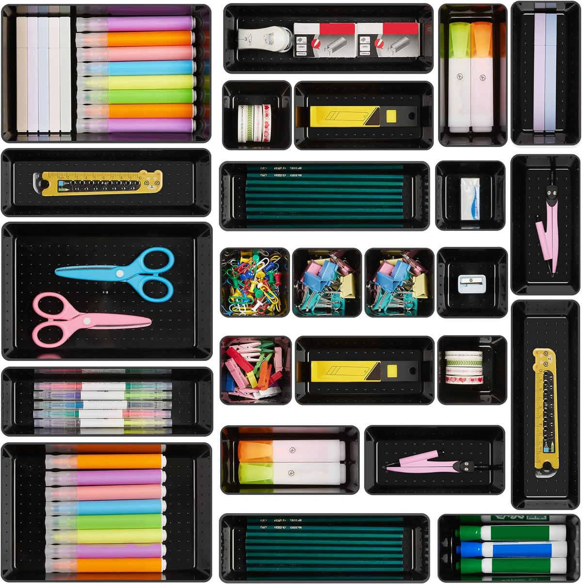 Black organizer trays displayed from above filled with pens, scissors, clips and office supplies