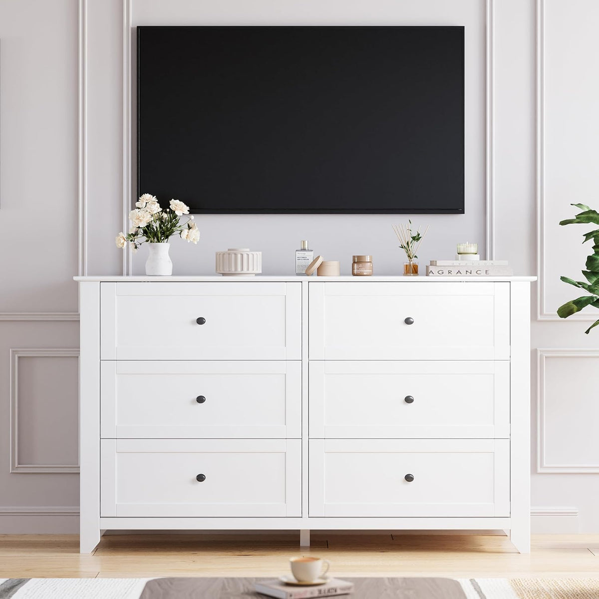 White dresser top under a mounted TV with tabletop decor, front view