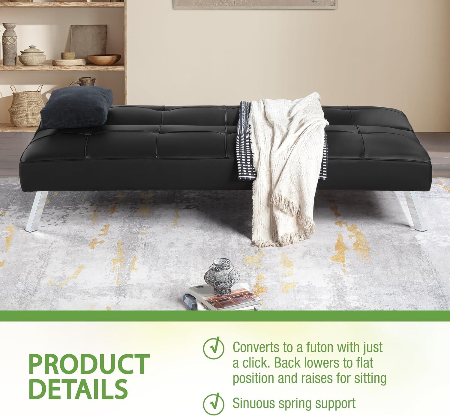 Black futon laid flat as a bed in a room, dressed with a blanket and pillow