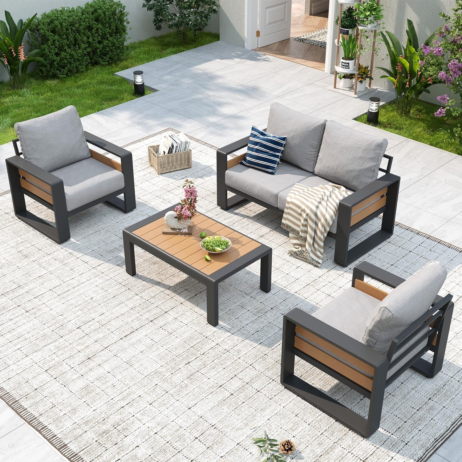 Overhead view of light-gray cushioned outdoor sofa and chairs with a wood-top coffee table on a patio rug.