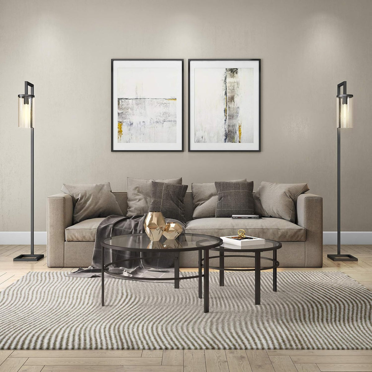 Black nested round tables in front of a beige sofa with a draped throw and gold geometric decor on the larger table.