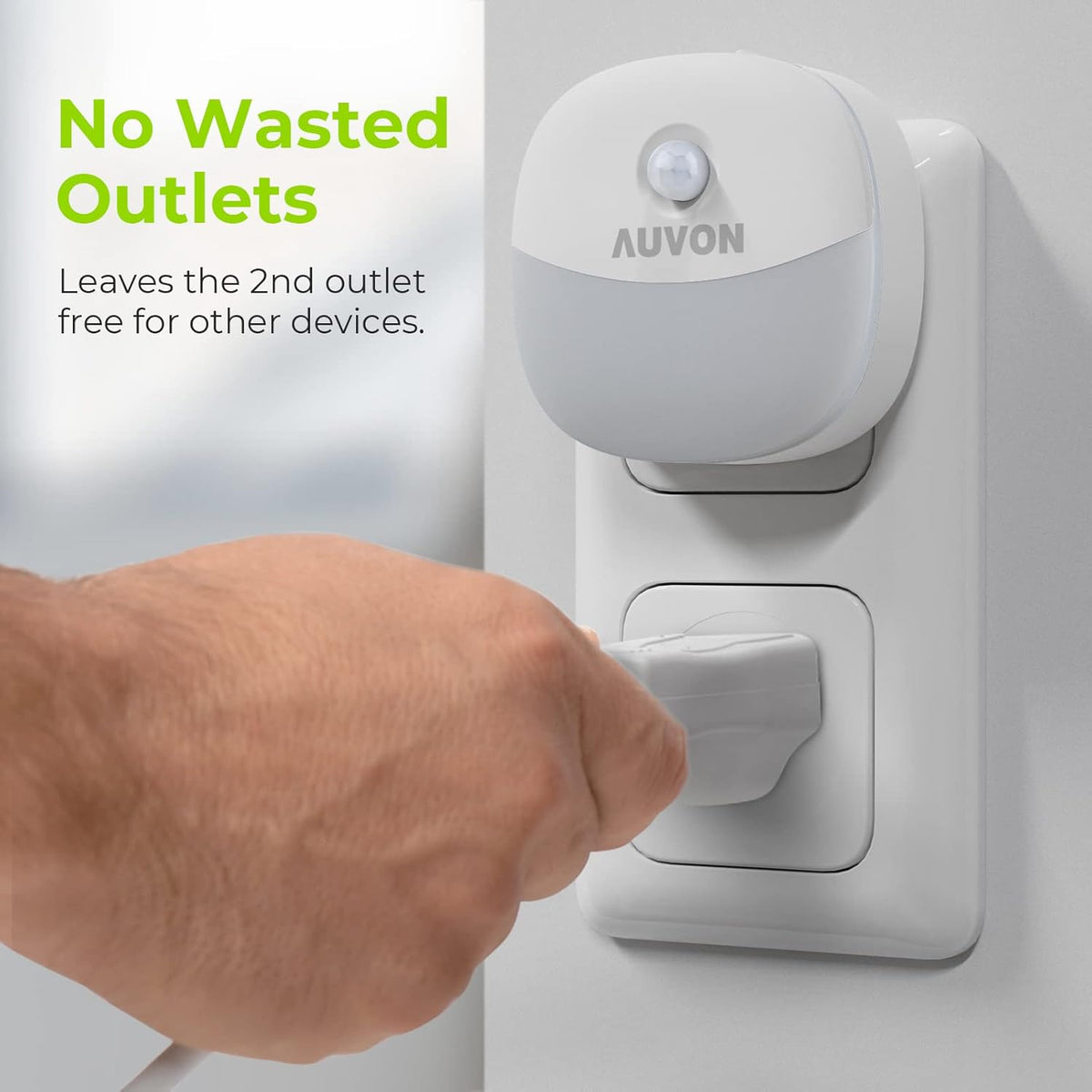 Close-up of the white night light occupying the top outlet while a hand plugs a cord into the bottom socket.
