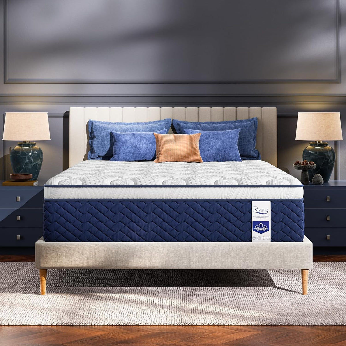 White and navy hybrid mattress on a beige upholstered bed frame, front view in a styled bedroom