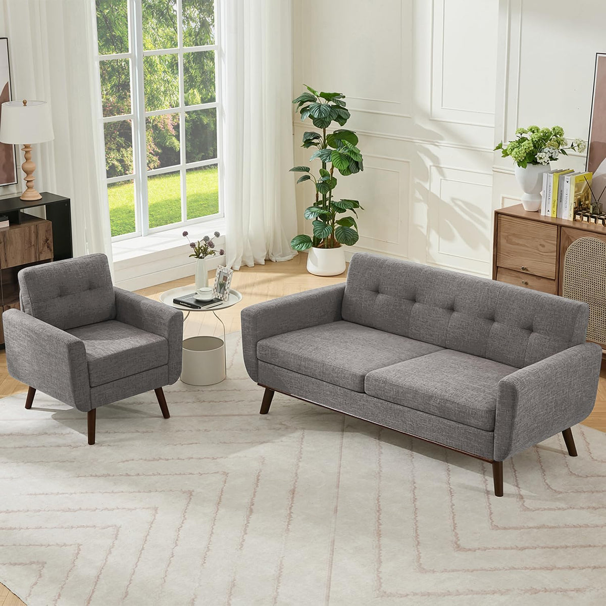 Gray upholstered loveseat and matching armchair arranged by a large window in a sunlit living room