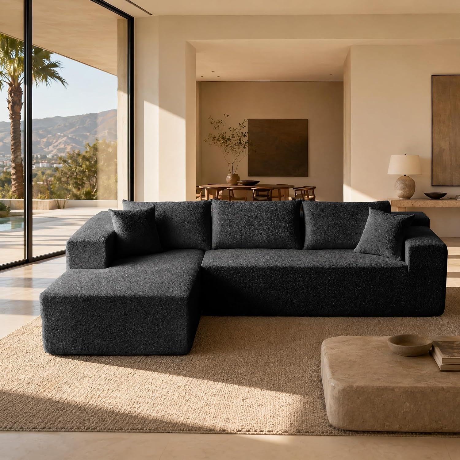 Front view of black 104-inch sectional with chaise and three back cushions in a sunlit room
