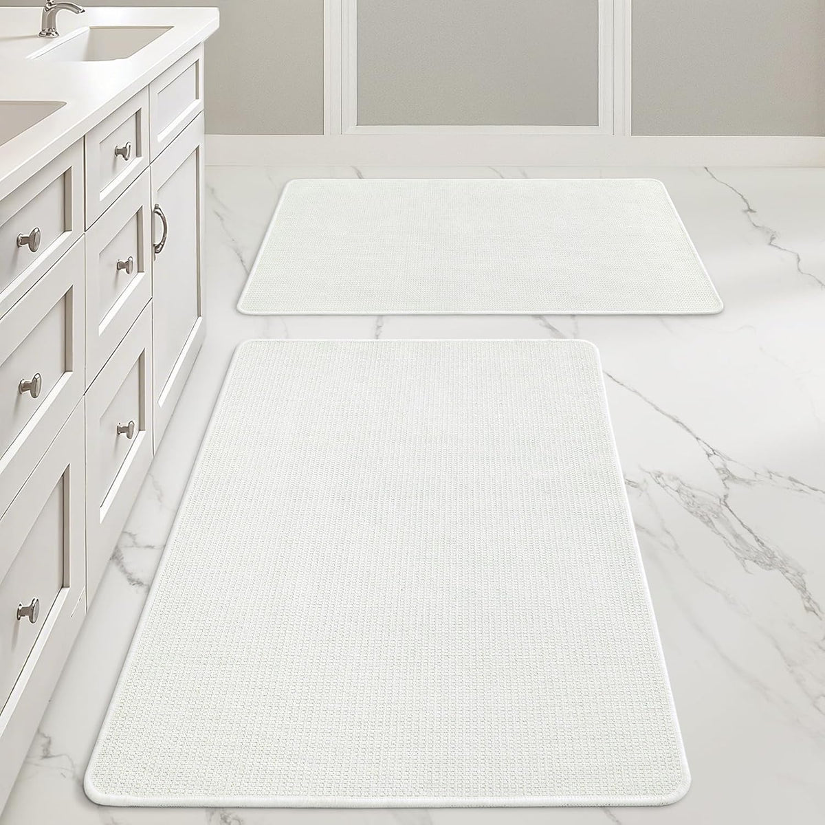 Bright, top-perspective bathroom scene with two white rectangular mats placed along the floor beside a double-sink vanity.