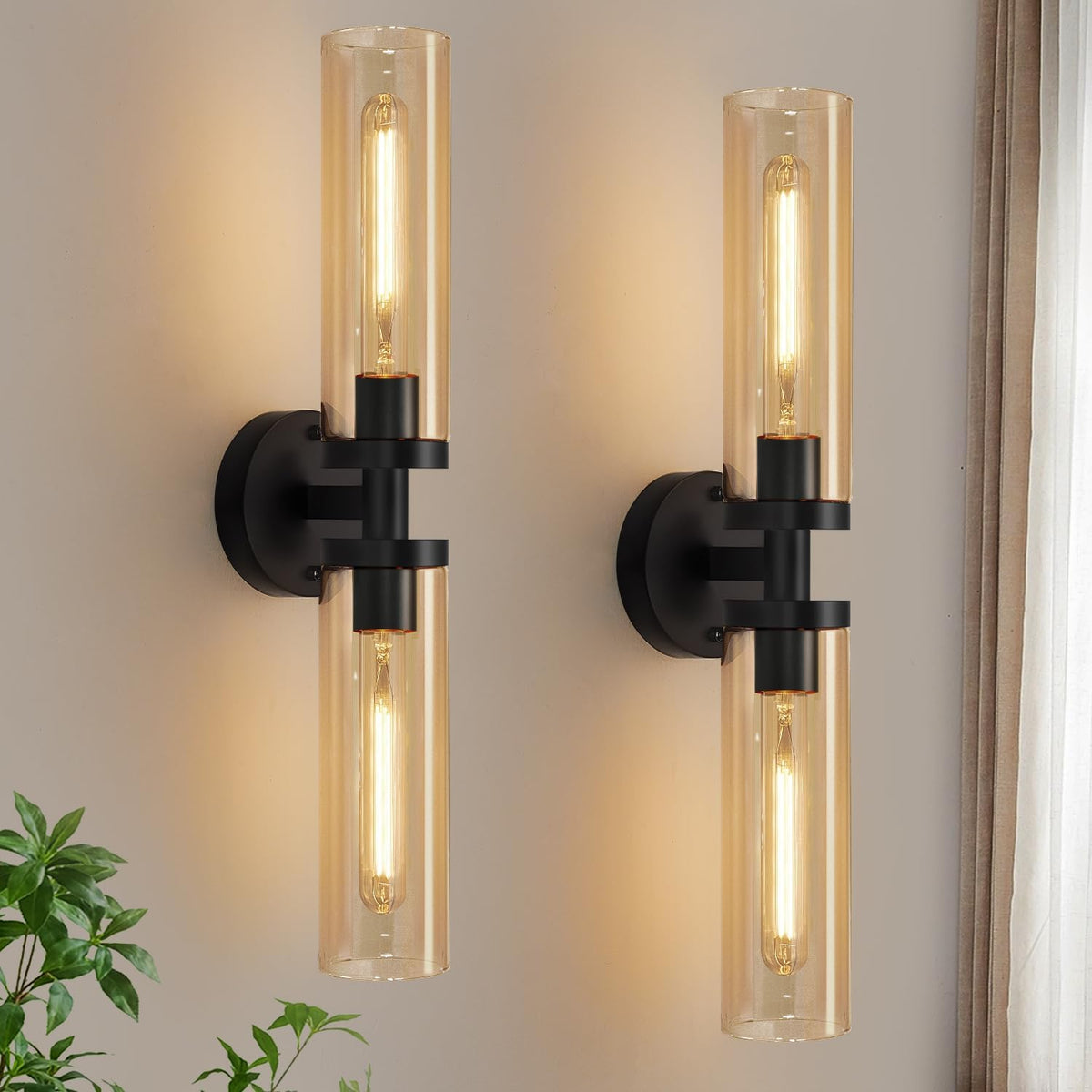 Pair of vertical matte-black wall sconces with amber-tinted glass tubes glowing on a neutral wall.