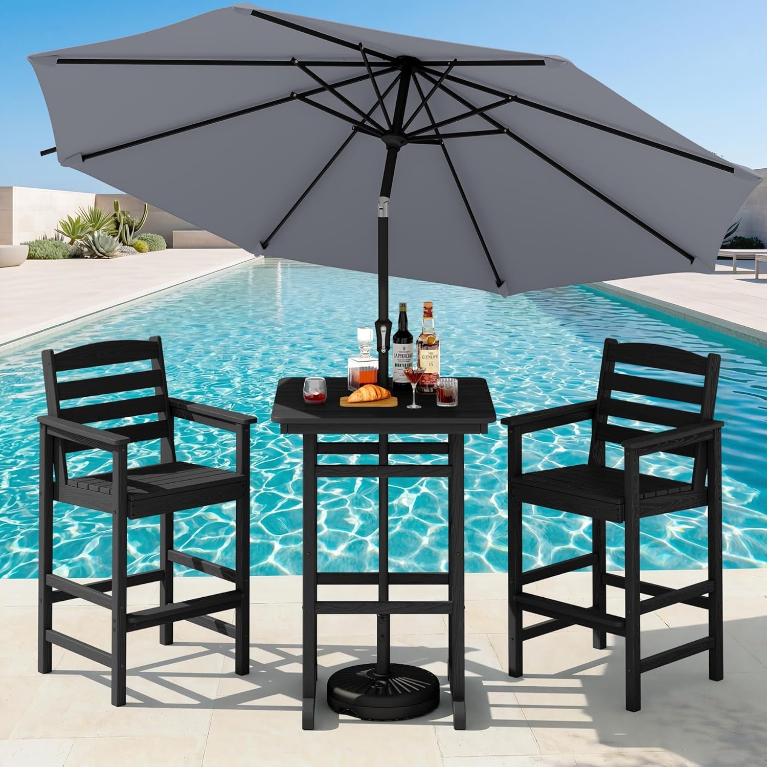 Dark charcoal bar table and two chairs arranged poolside under a large gray umbrella